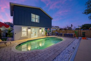 A modern two-story building with a swimming pool, a covered patio, and a wooden fence. - Palm Shell Villa - Pool - Pickleball - Hot Tub (Bradenton)