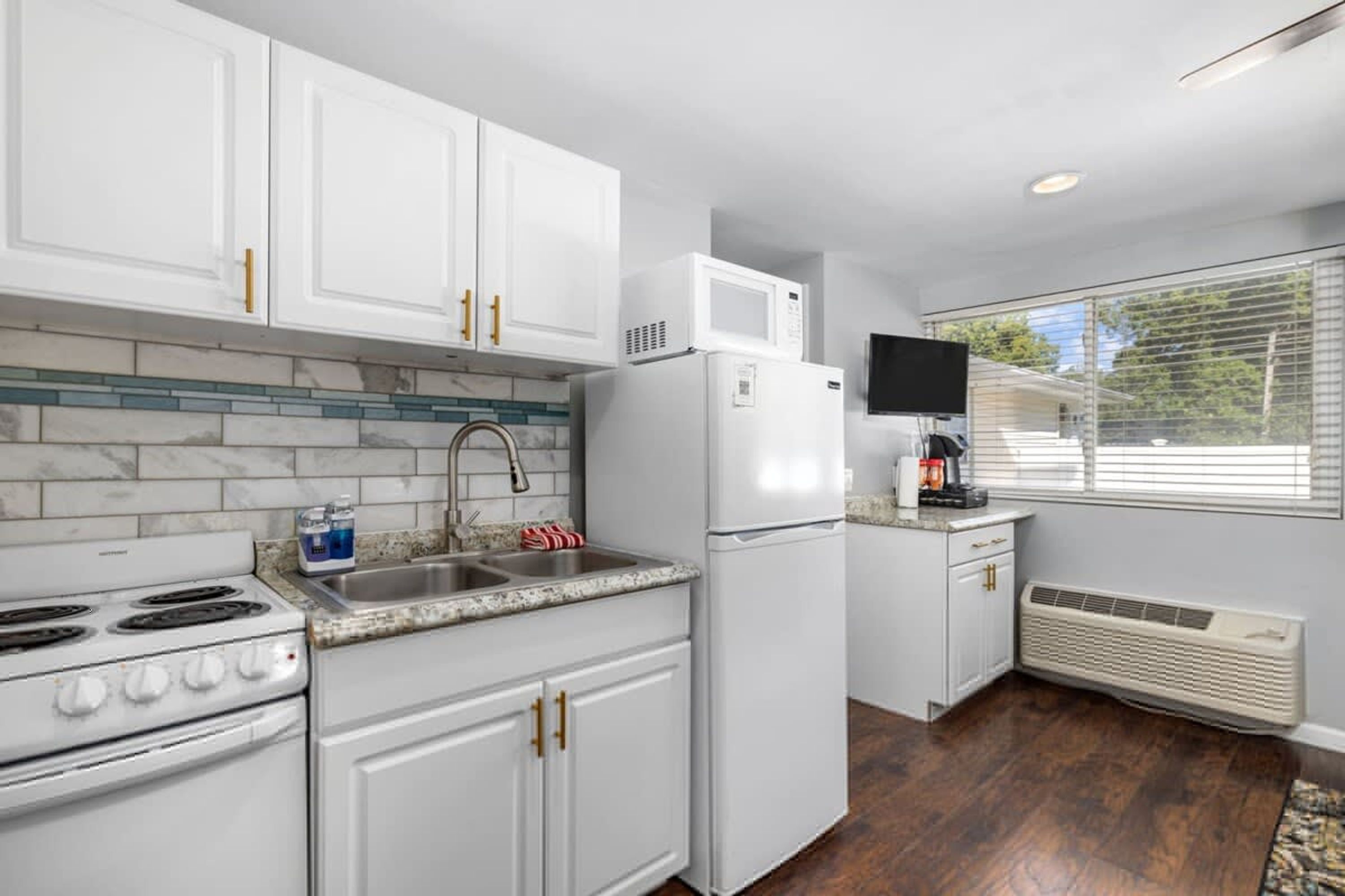 A kitchen with white cabinets, a stove, a microwave, and a sink.