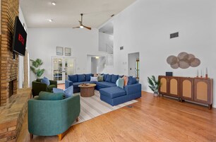 Uma sala de estar ampla com um sofá seccional, uma mesa de centro e uma lareira.