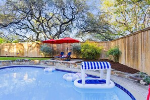 Ein Garten mit Swimmingpool, Liegestühlen und Holzzaun.