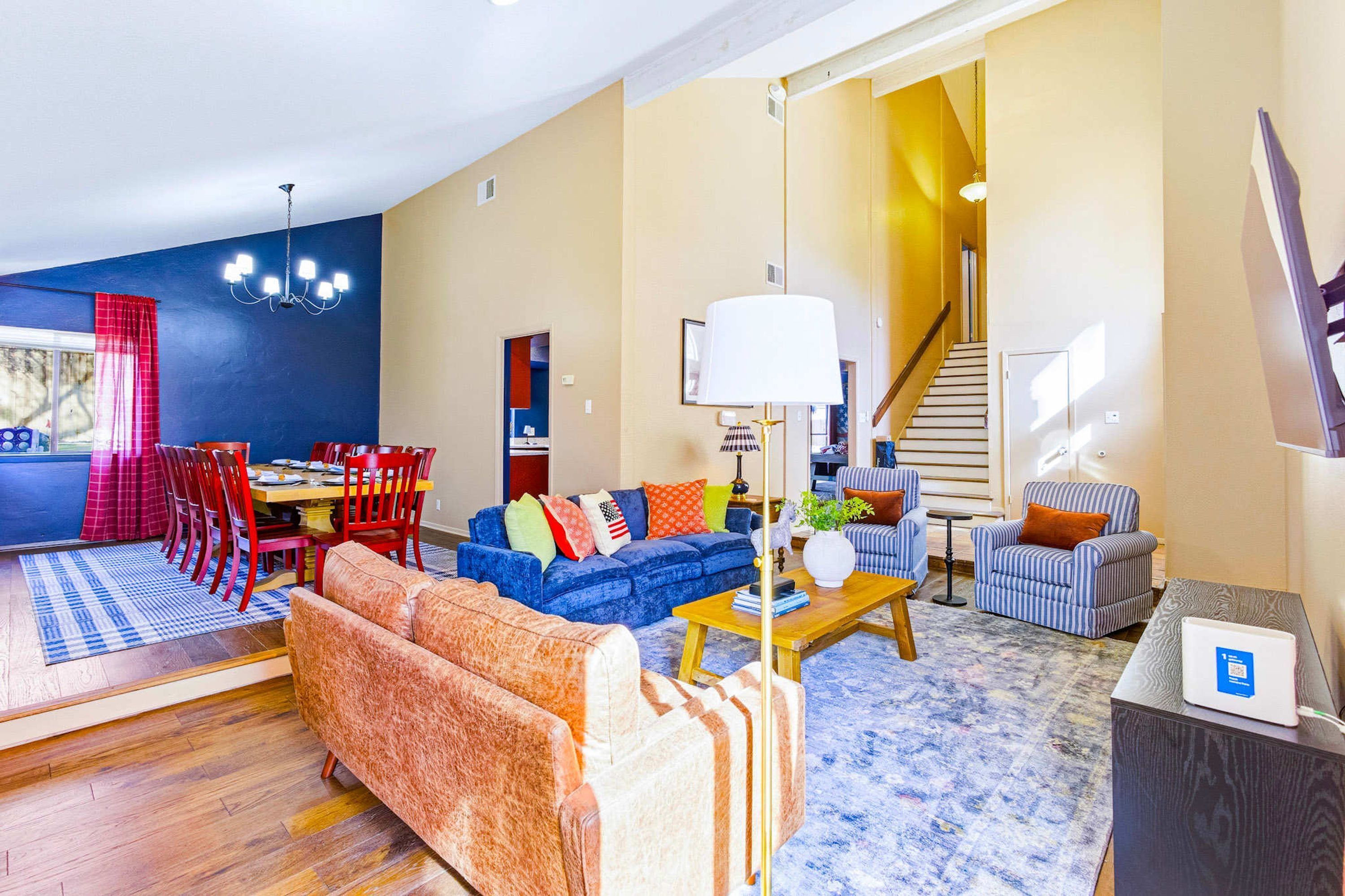 Una sala de estar moderna con comedor, una escalera y vistas al exterior.