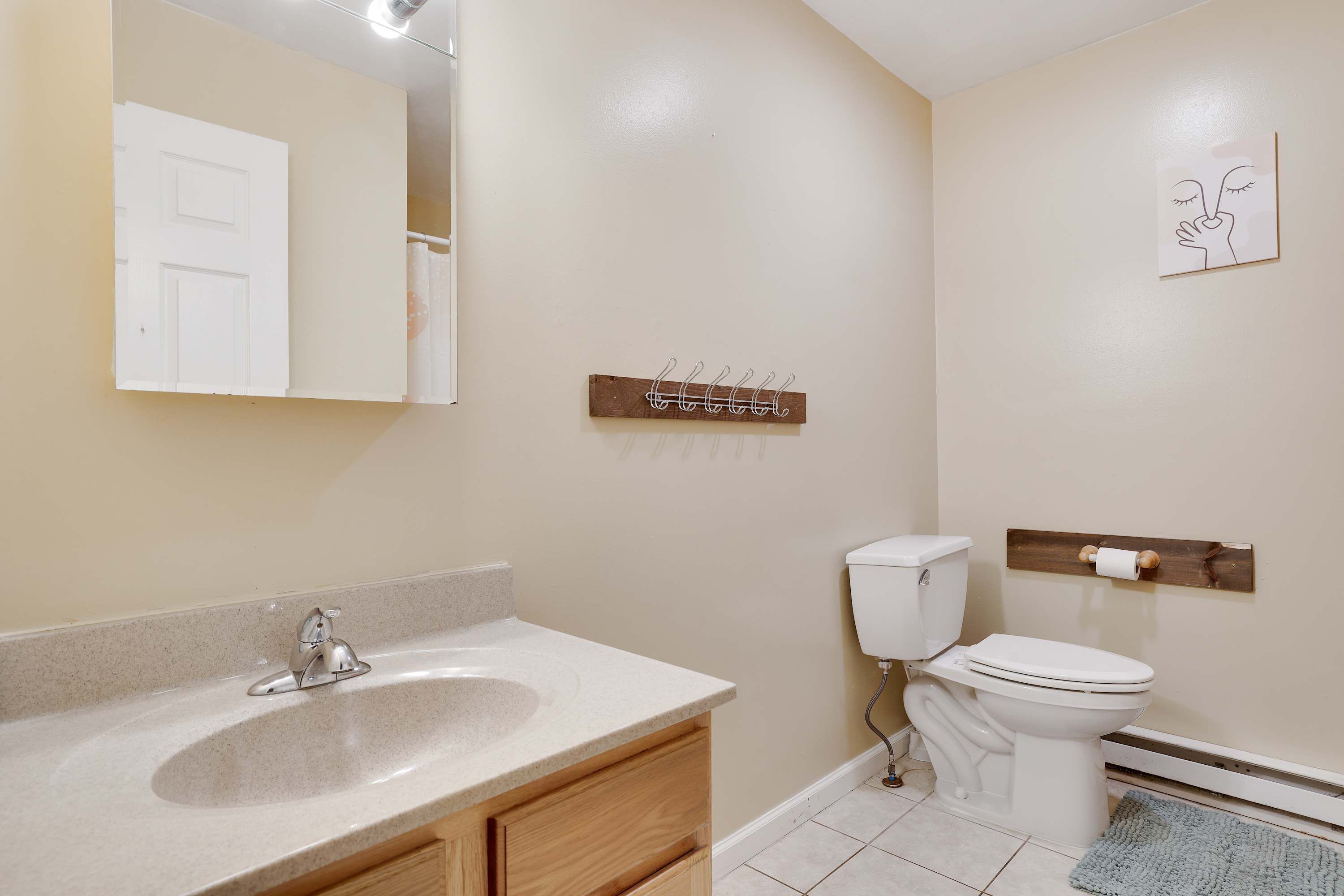 A bathroom with a sink, mirror, toilet, and a towel rack.