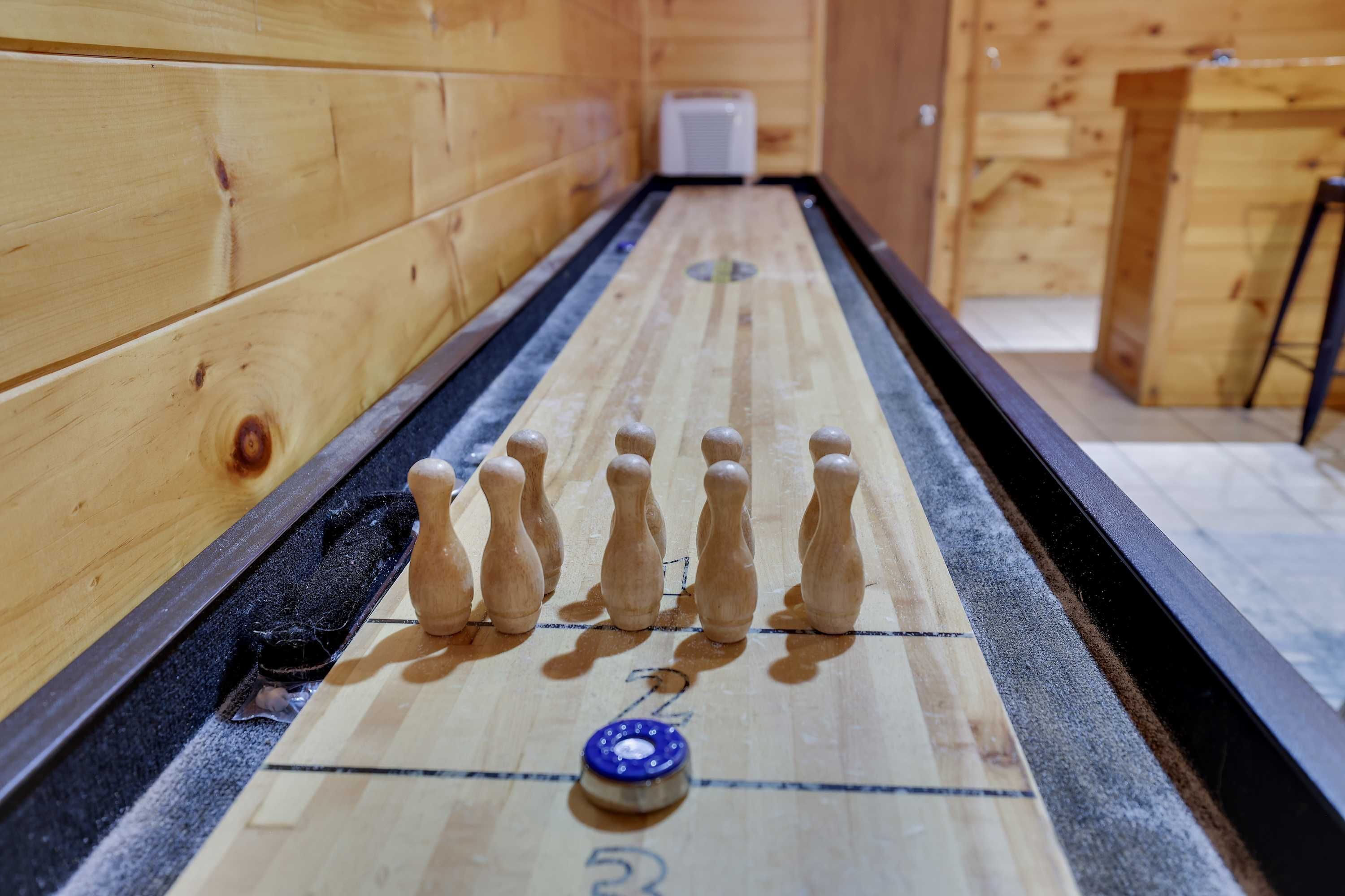 Una mesa de juego de shuffleboard con discos y un disco azul en el centro, frente a una pared de madera.