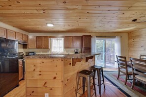 Une cuisine dotée de meubles en bois, d’un réfrigérateur en acier inoxydable, d’un comptoir en granit et d’un grand îlot central avec des tabourets.