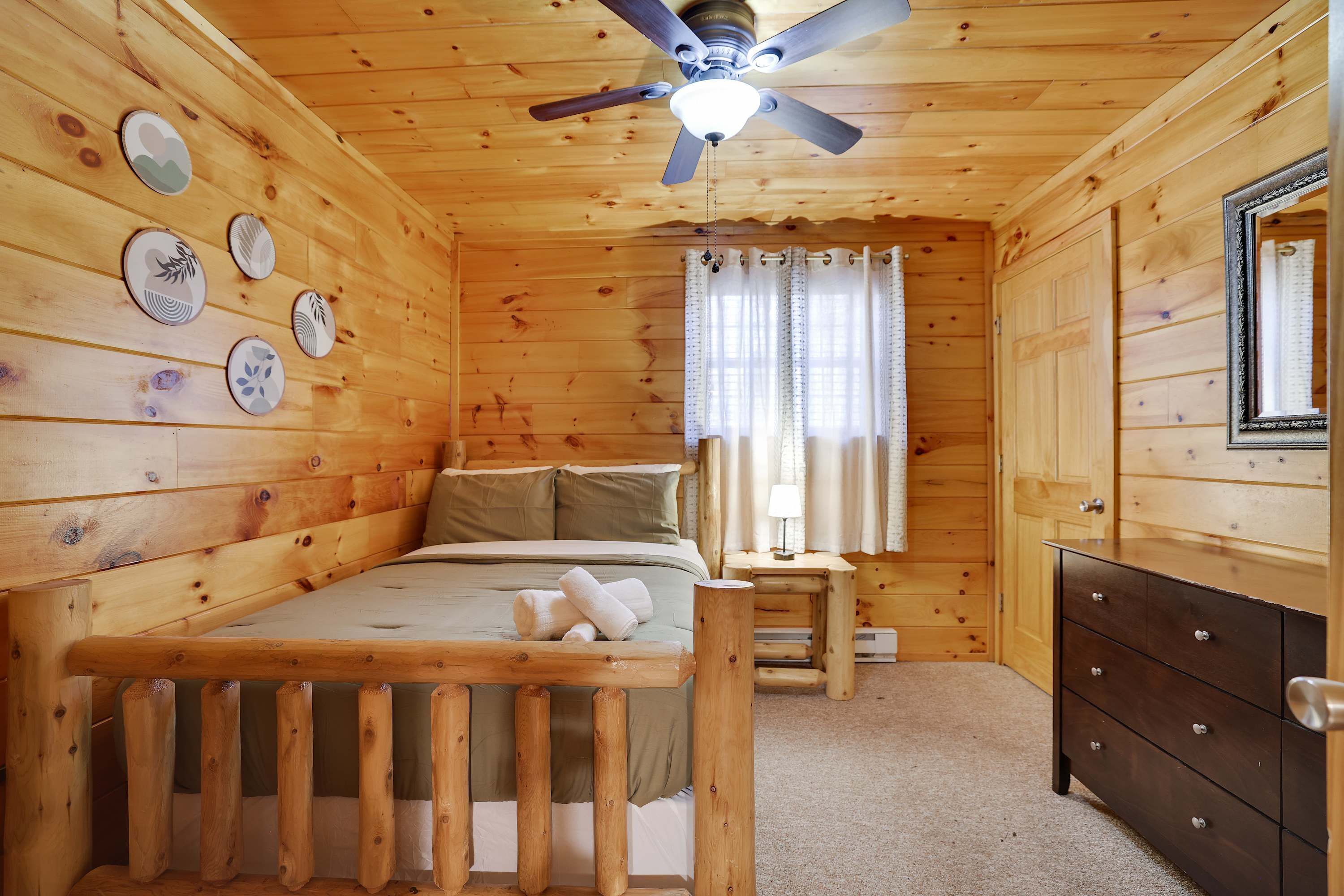 Quarto de cabana de madeira com cama, cômoda e ventilador de teto.
