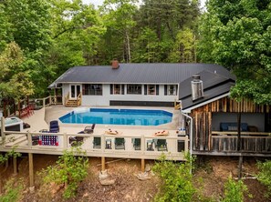 Ein zweistöckiges Haus mit Swimmingpool, Liegestühlen und einer Holzterrasse.