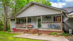 A single-story house with a front porch, a green door, and a brick foundation. - Wellsprings Retreat Smoky Mtn Views Sleeps 12 (Gatlinburg)