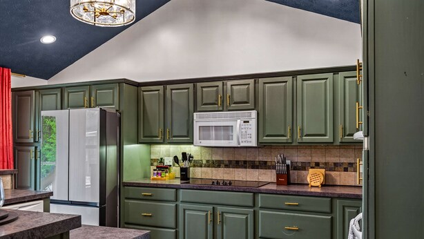 A kitchen with green cabinets, a white refrigerator, a microwave, and a wooden countertop. - Wellsprings Retreat Smoky Mtn Views Sleeps 12 (Gatlinburg)