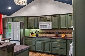 A kitchen with green cabinets, a white refrigerator, a microwave, and a wooden countertop. - Wellsprings Retreat Smoky Mtn Views Sleeps 12 (Gatlinburg)