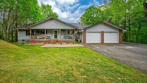 A two-story house with a front porch, a garage, and a well-maintained lawn. - Wellsprings Retreat Smoky Mtn Views Sleeps 12 (Gatlinburg)
