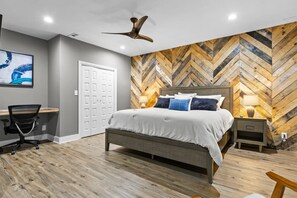 A bedroom with a bed, desk, chair, and a herringbone-patterned wall. - Mtn Views Theater Hot Tub 5 King Suites (Blue Ridge)