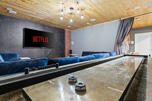 A modern lounge area with a Netflix screen, blue seating, and a pool table. - Mtn Views Theater Hot Tub 5 King Suites (Blue Ridge)