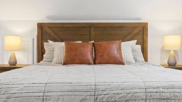 A bed with a wooden headboard, two nightstands with lamps, and multiple pillows.