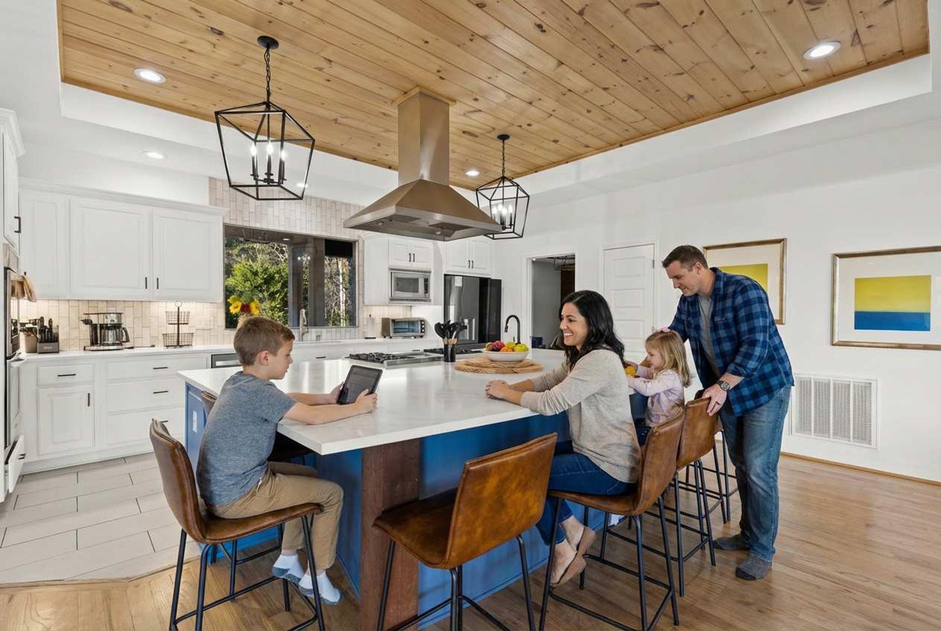 A modern kitchen with white cabinets, a central island, and pendant lighting.
