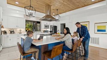 A modern kitchen with white cabinets, a central island, and pendant lighting.