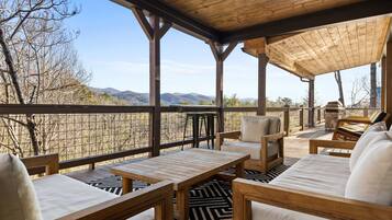 A covered outdoor seating area with wooden furniture and a view of mountains.