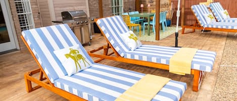 Un patio con dos sillones de descanso, una parrilla y una zona de comedor.