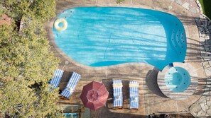 Vue aérienne d’une piscine avec des chaises longues et des parasols.