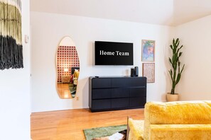 A modern living room with a flat-screen TV, a mirror, a sofa, and a potted plant. - Upscale Escape Pool Hot Tub Game Room Firepit (San Antonio)