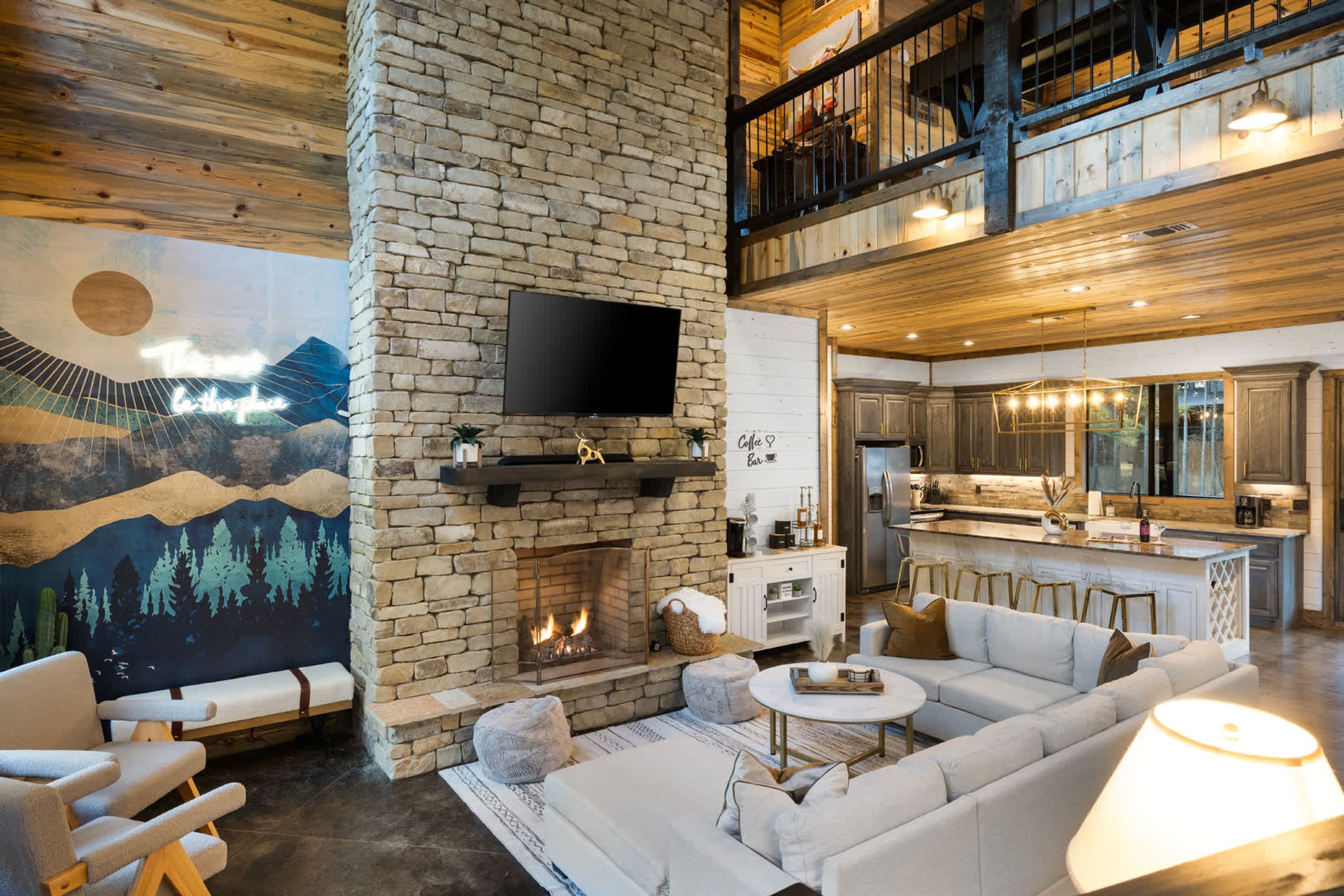 A spacious living area with a stone fireplace, a large flat-screen TV mounted on the wall, and a cozy seating arrangement.