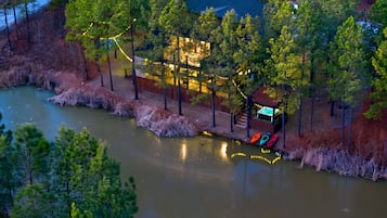 A riverside property with a dock, boats, and a building with string lights.