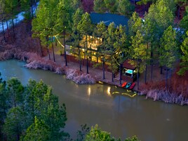 A riverside property with a dock, boats, and a building with string lights.