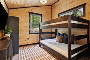 A bunk bed with pillows, a small table with a bowl, and a window with a view of trees. - Elevated Smoky Mountain Escape Hot Tub Views (Sevierville)