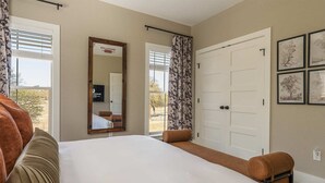 Quarto de hotel com uma cama grande, um espelho, um guarda-roupa e vista para o exterior.