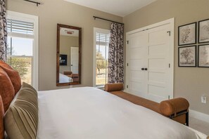 Ein Hotelzimmer mit einem großen Bett, einem Spiegel, einem Kleiderschrank und Blick ins Freie.