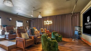 Uma sala de estar espaçosa com sofás de couro, poltronas de grão de bico verde e uma parede com tela grande.