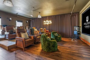 Ein geräumiges Wohnzimmer mit Ledersofas, grünen Sitzsäcken und einer großen Bildschirmwand.