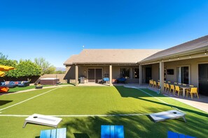A building with a covered patio area, outdoor seating, and a well-maintained lawn. - Suncrest Retreat - Pool Pickleball Theater (Scottsdale)