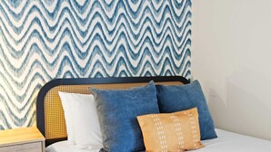 A bed with a headboard, a wooden nightstand, and a wall with a zigzag patterned wallpaper. - Suncrest Retreat - Pool Pickleball Theater (Scottsdale)