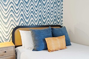 A bed with a headboard, a wooden nightstand, and a wall with a zigzag patterned wallpaper. - Suncrest Retreat - Pool Pickleball Theater (Scottsdale)