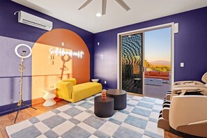 Un salon moderne avec un tapis à carreaux, un canapé jaune et une porte vitrée donnant sur un espace extérieur.