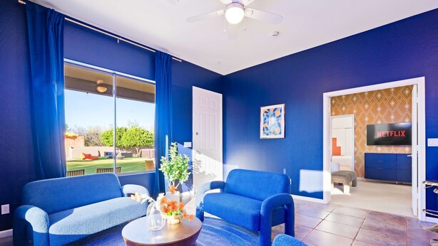 A living room with two blue sofas, a coffee table, and a TV in the background. - Suncrest Retreat - Pool Pickleball Theater (Scottsdale)