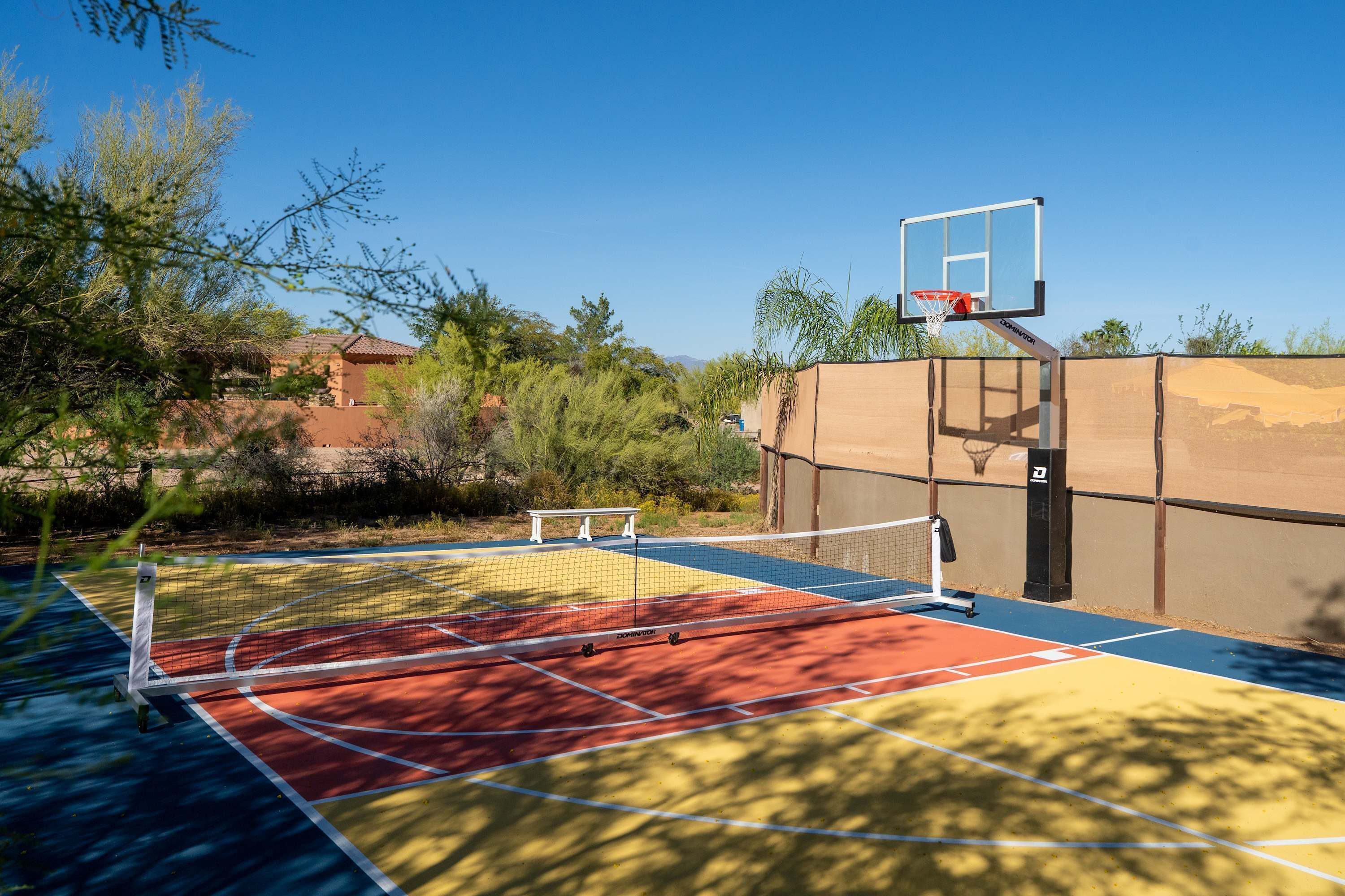 An outdoor basketball court with a net, a basketball hoop, and a bench.