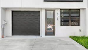 A modern building with a large garage door, a garage door number, and a window with blinds. - Brand New Tampa Townhouse Prime Location (Tampa)