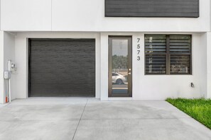 A modern building with a large garage door, a garage door number, and a window with blinds. - Brand New Tampa Townhouse Prime Location (Tampa)