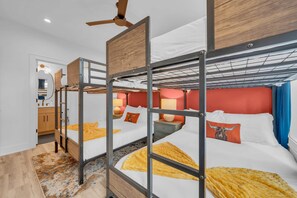 A bunk bed room with a ceiling fan, a bathroom with a mirror, and a patterned rug. - Nashville Hideaway - Rooftop Patio w City Views (Nashville)