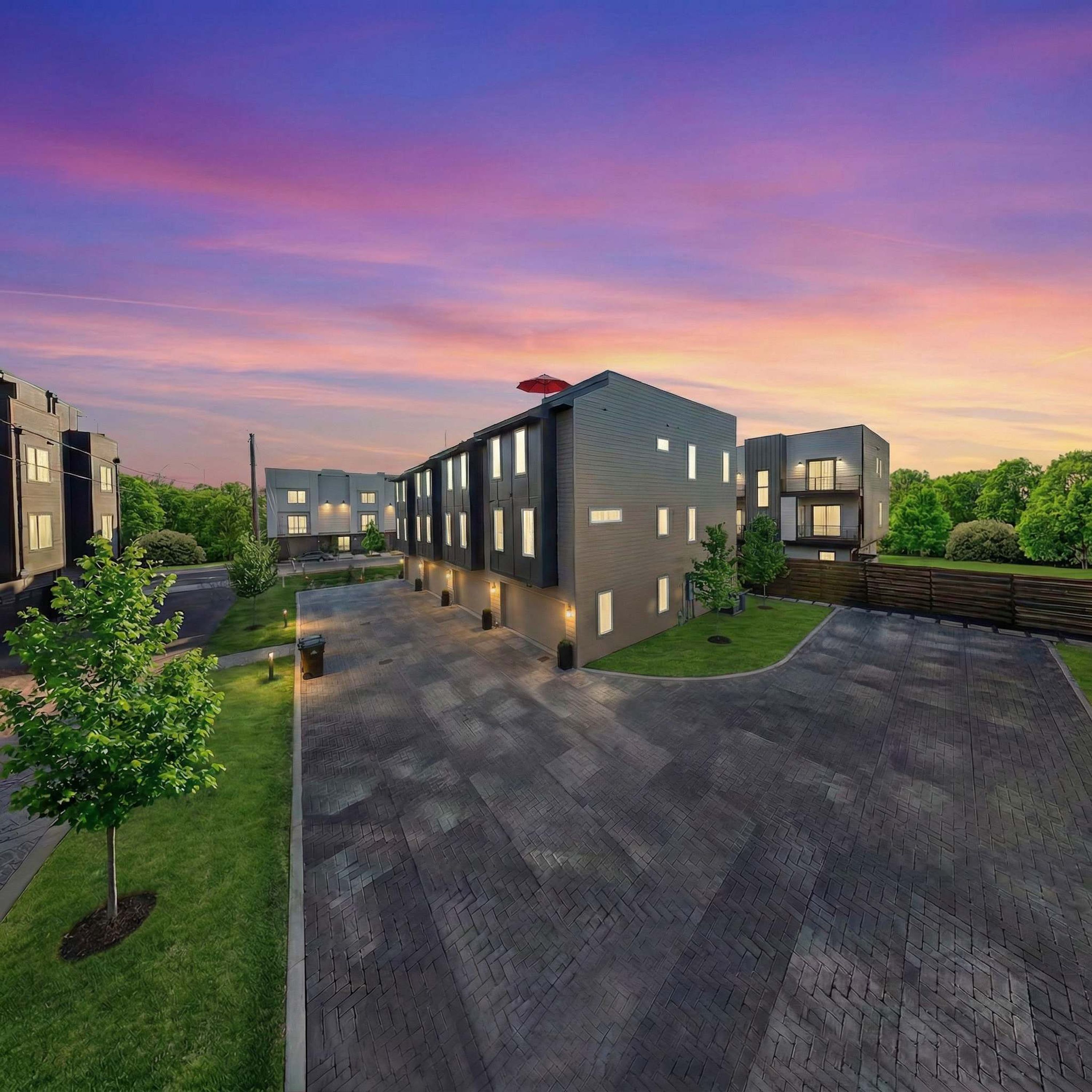 A modern building complex with a paved courtyard, surrounded by greenery.