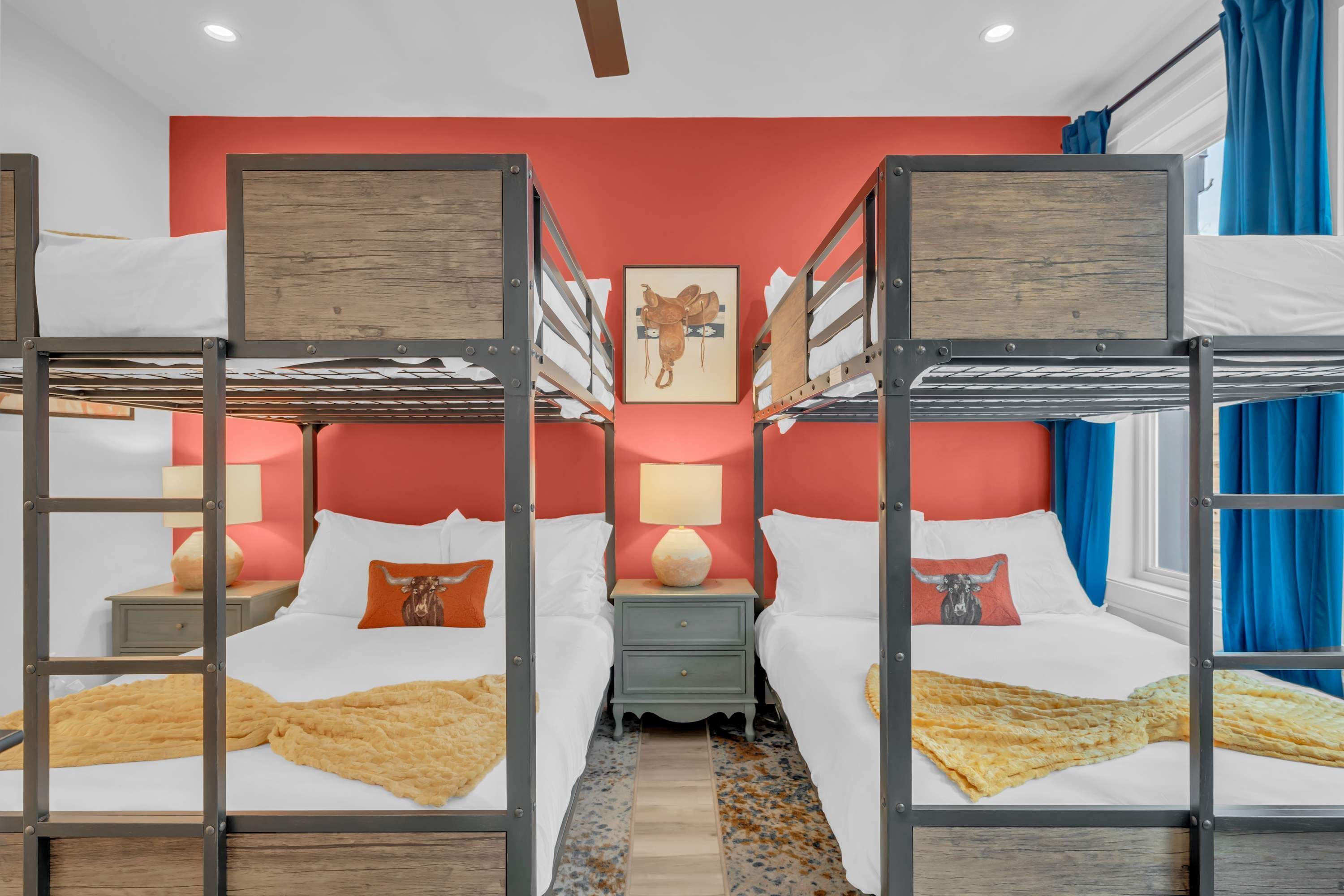 Habitación de hotel con literas, una mesita de noche central con lámpara y una obra de arte colgada en la pared.