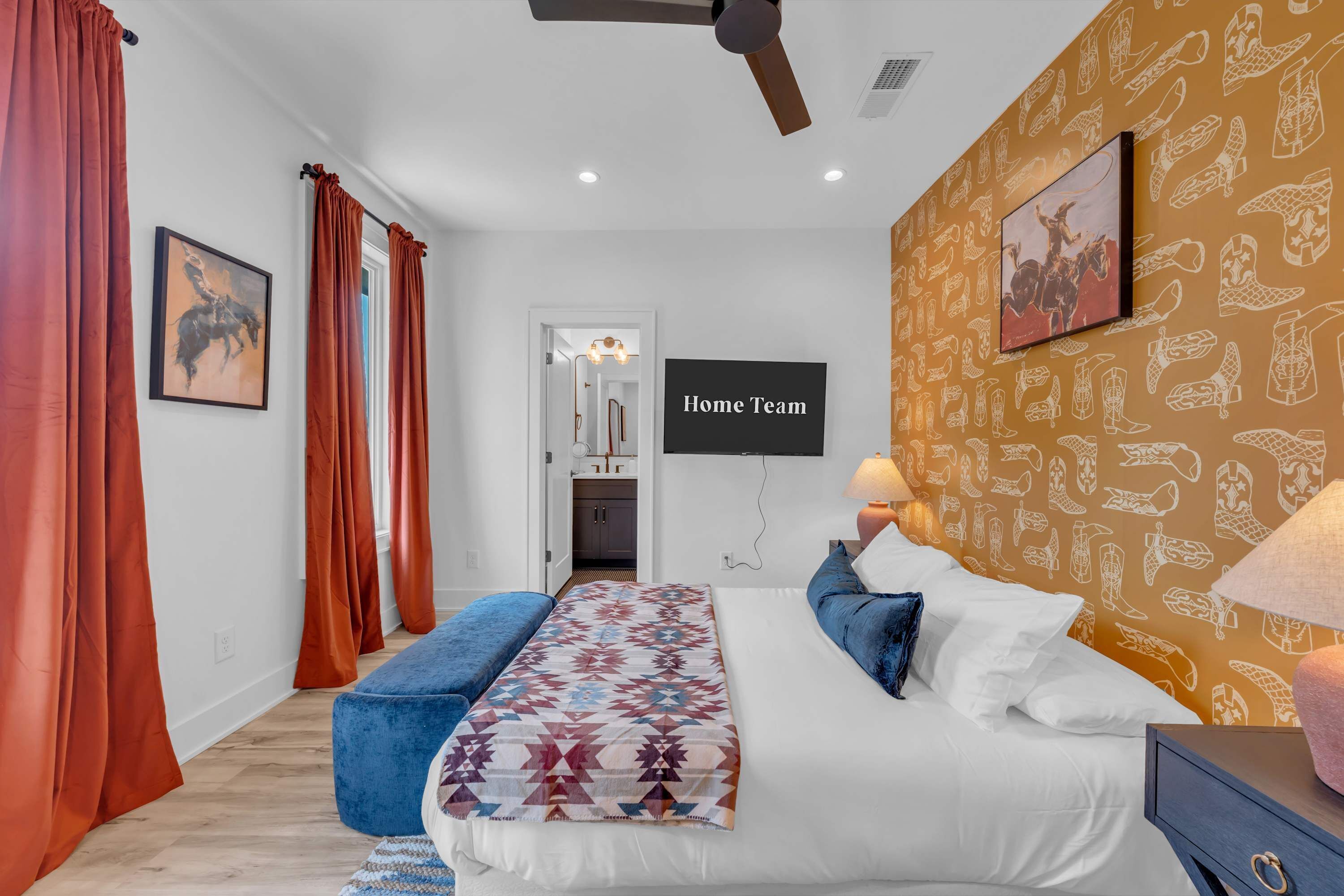 Une chambre à coucher avec un lit, un banc, une télévision et un mur décoré de motifs.
