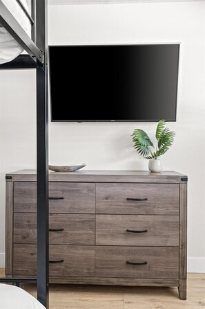Ein modernes Zimmer mit einem grauen Holzschrank, einem flachbildfernseher an der Wand und einem Blumentopf auf dem Schrank.
