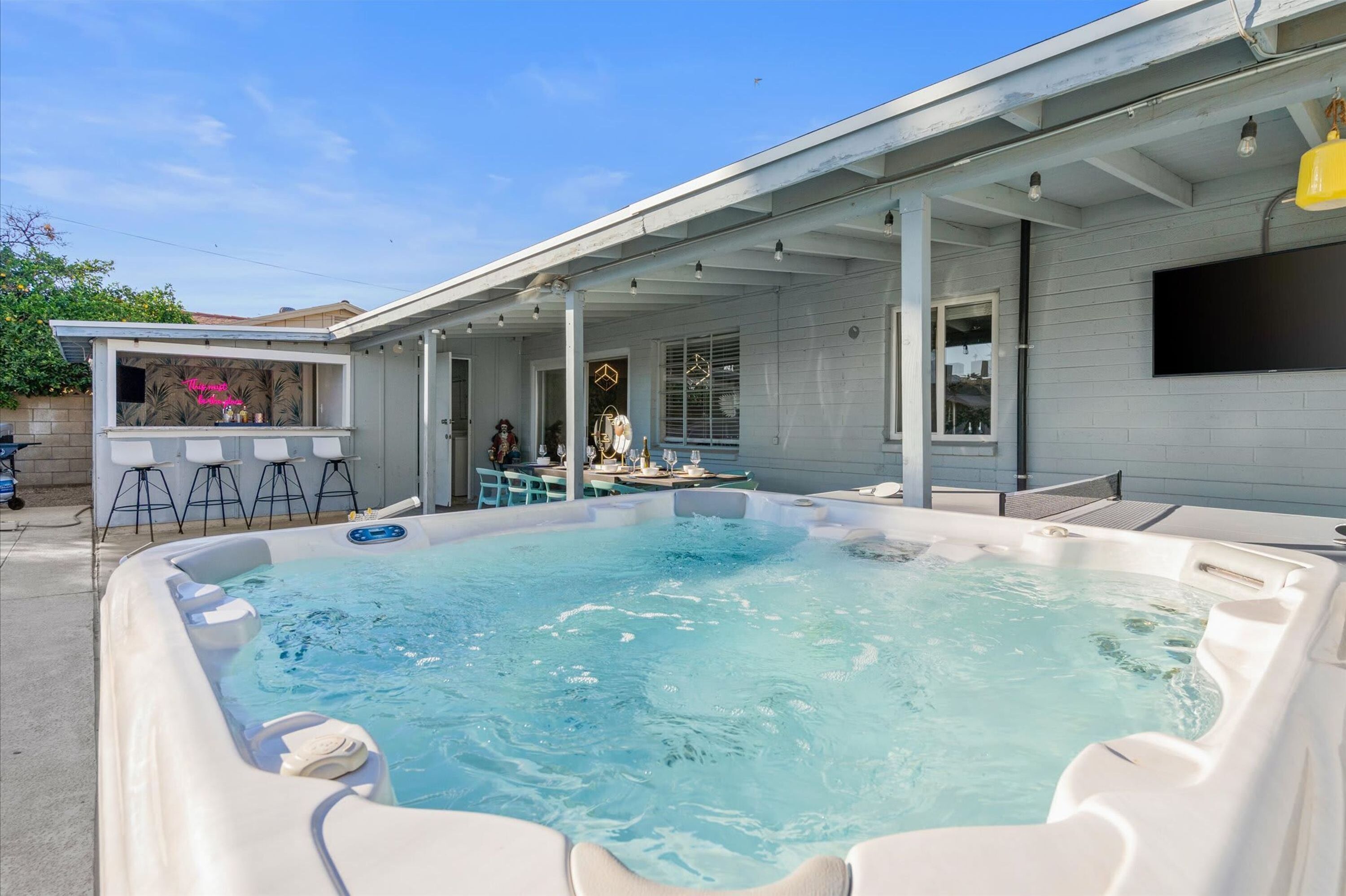 Un jardin avec un jacuzzi, un espace salon extérieur et une terrasse couverte.