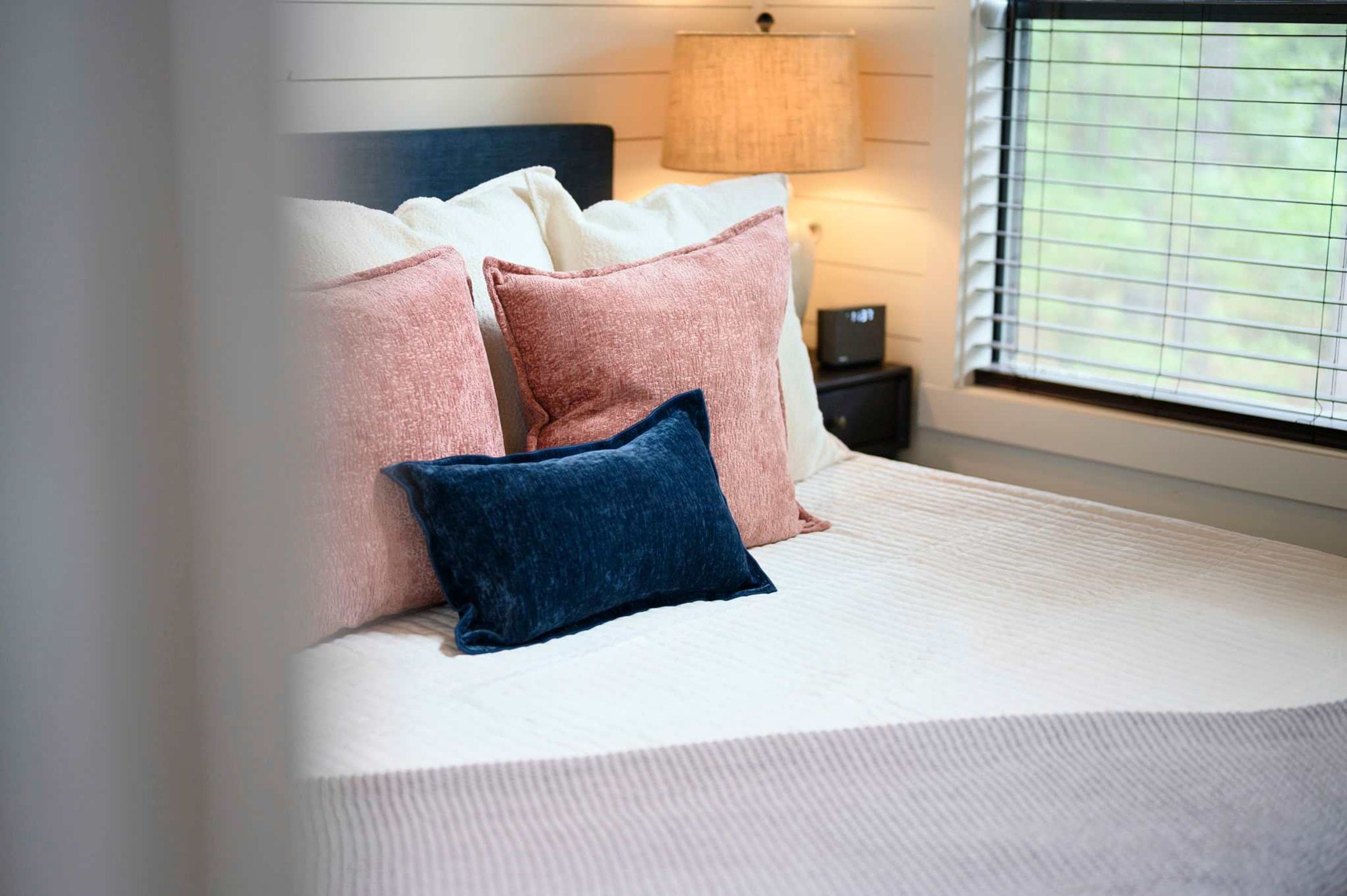 Una cama con varias almohadas y una lámpara de noche.