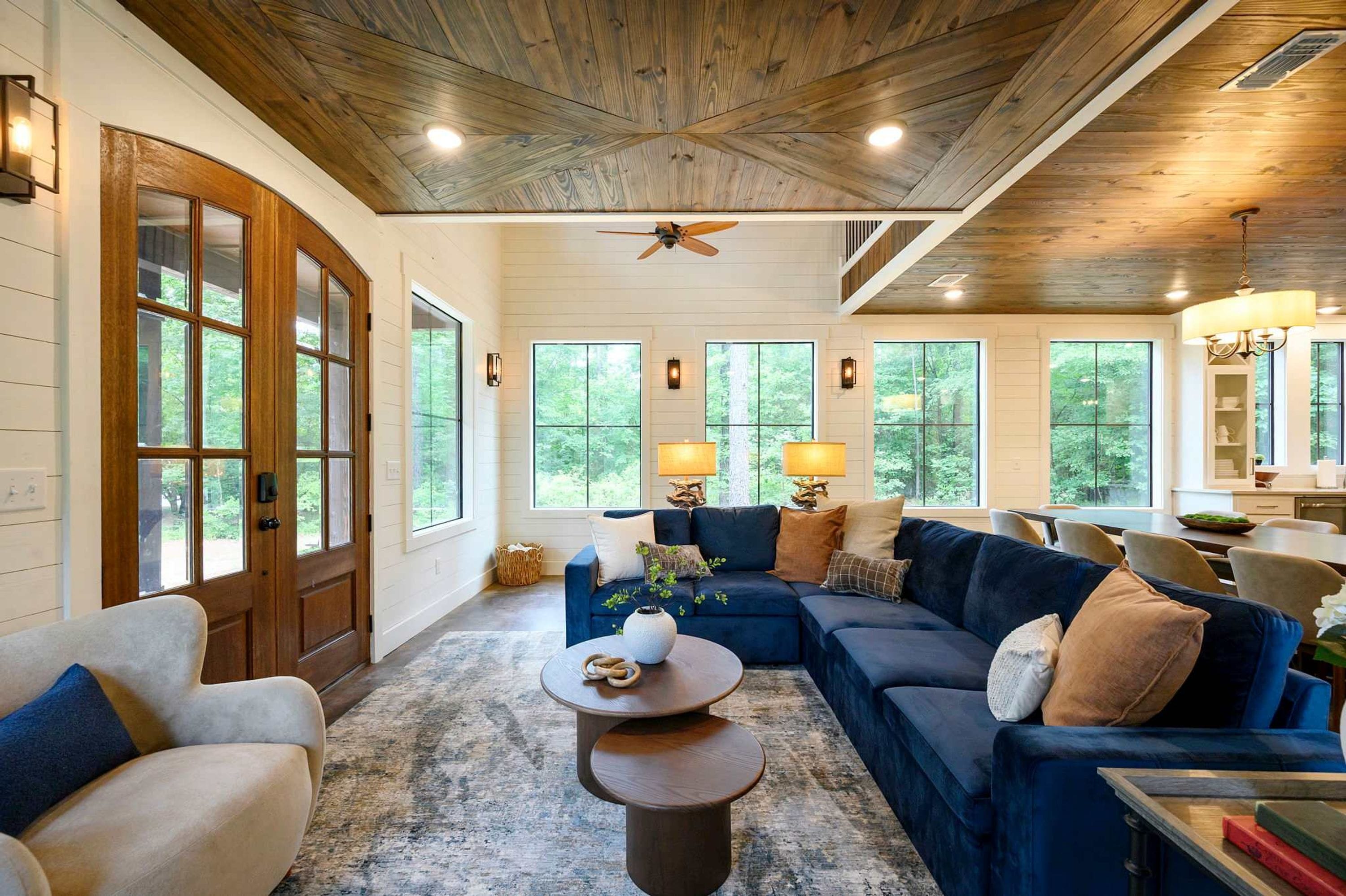 A spacious living room with a large blue sofa, a wooden coffee table, and a ceiling fan.