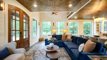 A spacious living room with a large blue sofa, a wooden coffee table, and a ceiling fan.