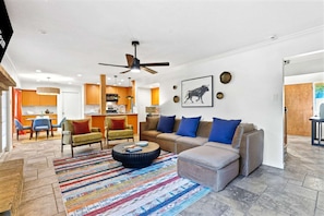 A modern living room with a sofa, coffee table, and a dining area in the background. - Elegant Escape Sleeps 14 Games Pool Fire Pit (San Antonio)