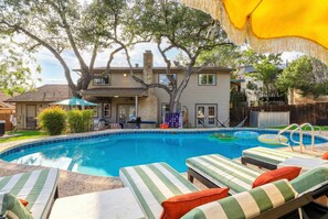 A backyard with a swimming pool, lounge chairs, and a large tree. - Elegant Escape Sleeps 14 Games Pool Fire Pit (San Antonio)